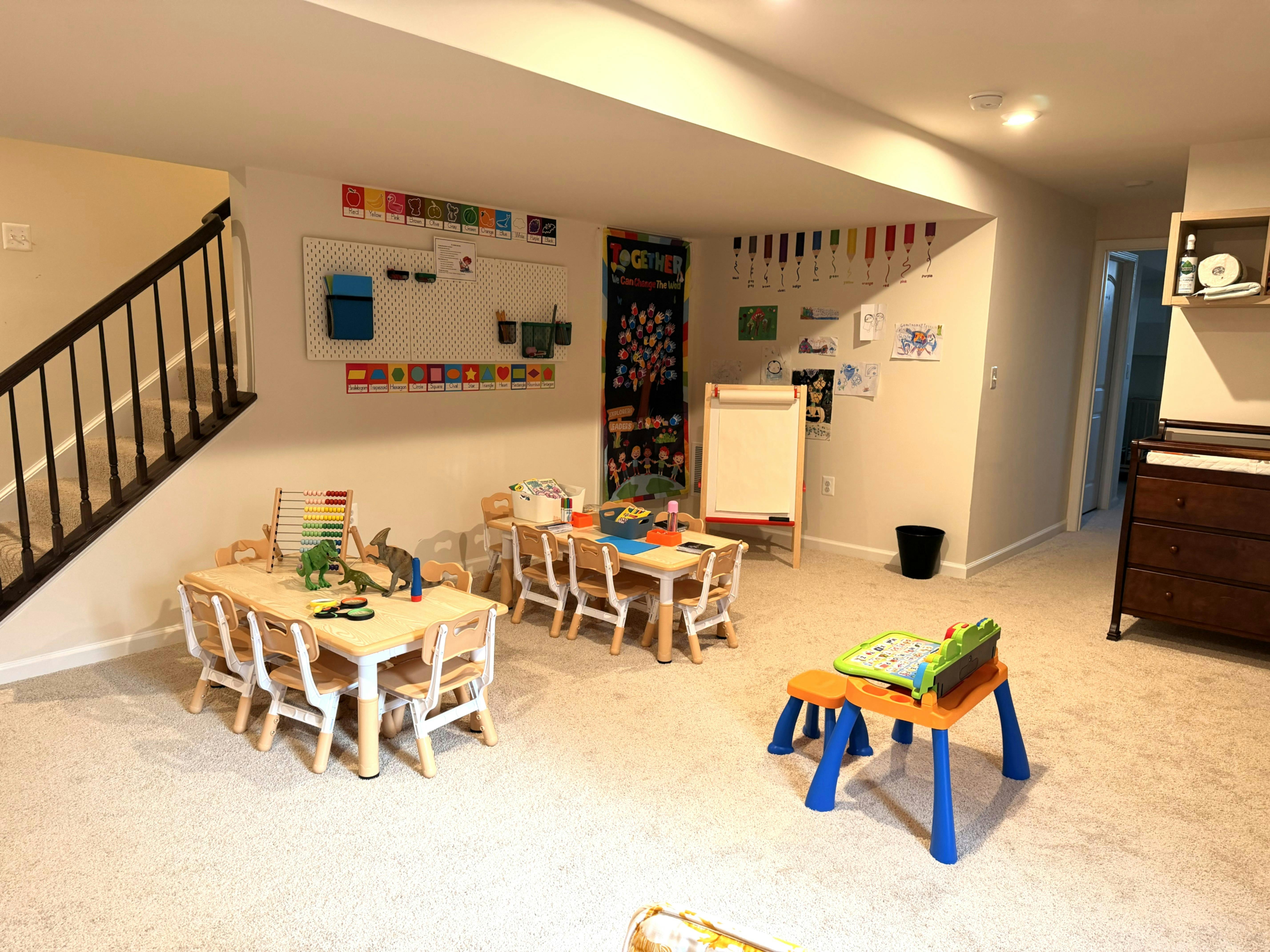 children's play space with small tables and chairs, white board, and art supplies