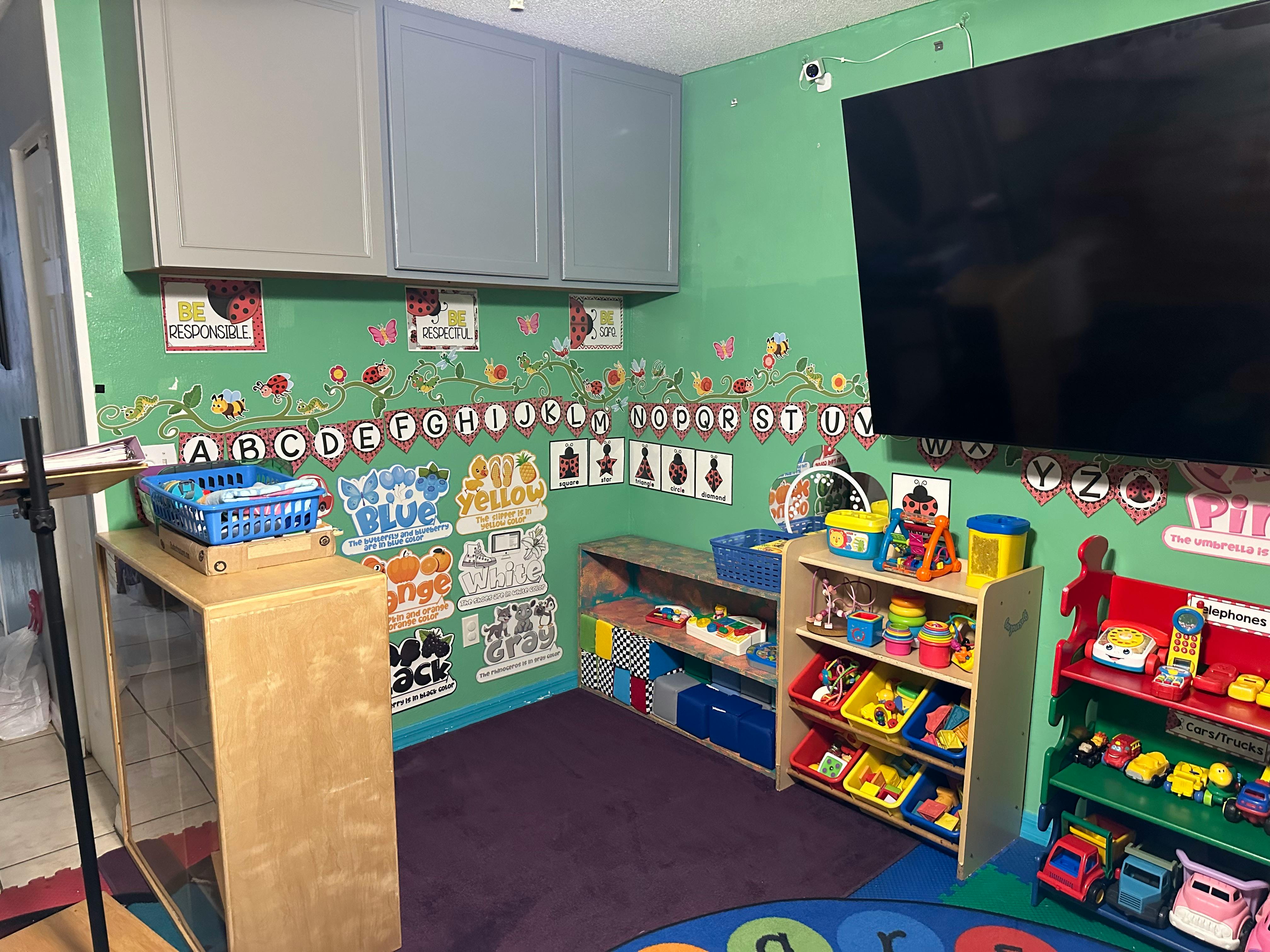 Classroom with alphabet decorations, shelves of toys, and a large screen