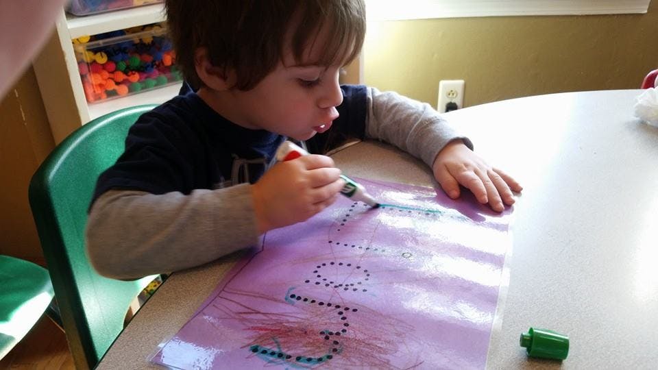 Child drawing on paper with a marker