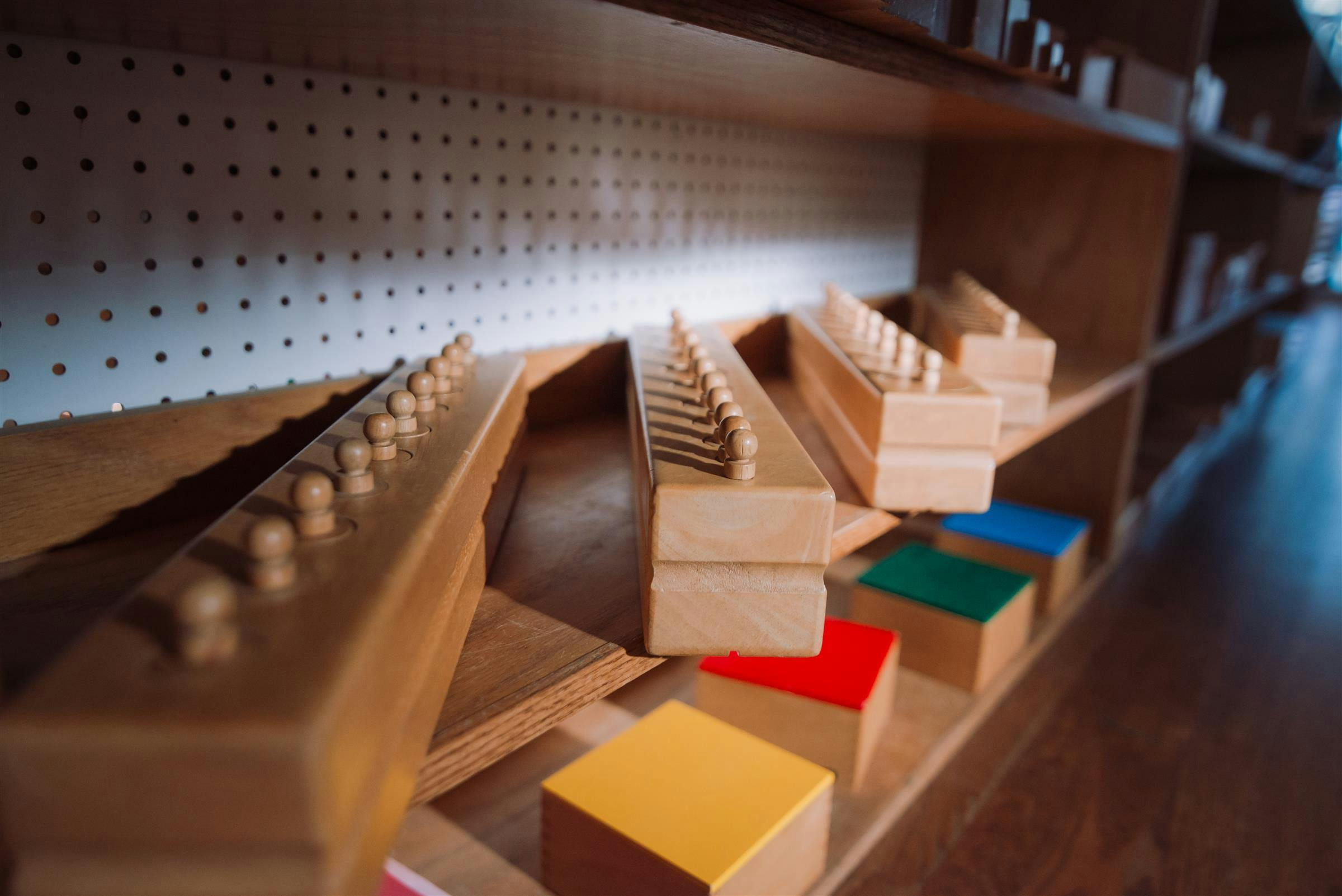 Wooden Montessori knobbed cylinders and colored blocks on a shelf