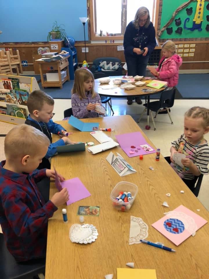 Children doing crafts at a table in a classroom