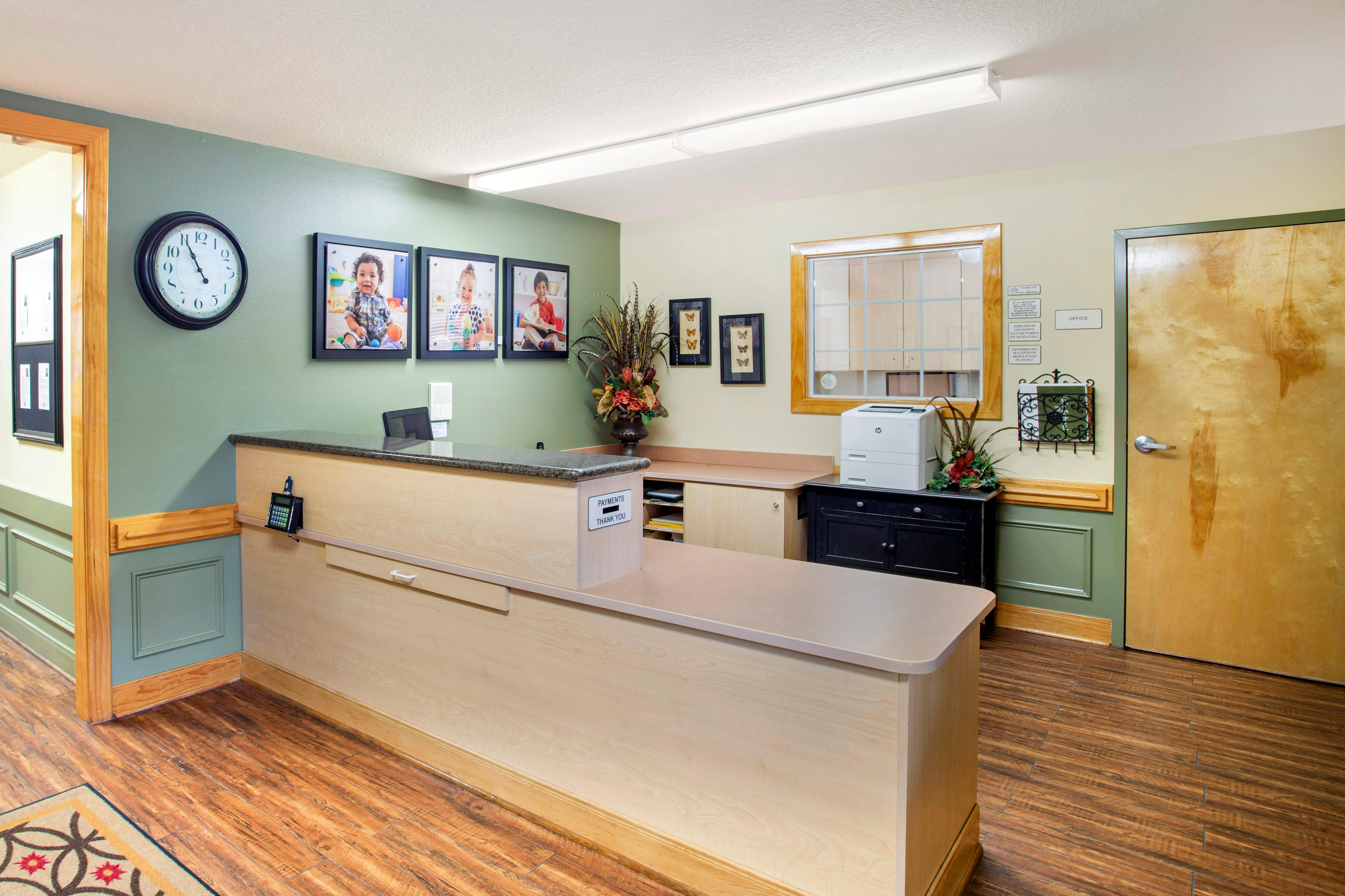 Reception desk with framed photos of children and a payments drop-off slot