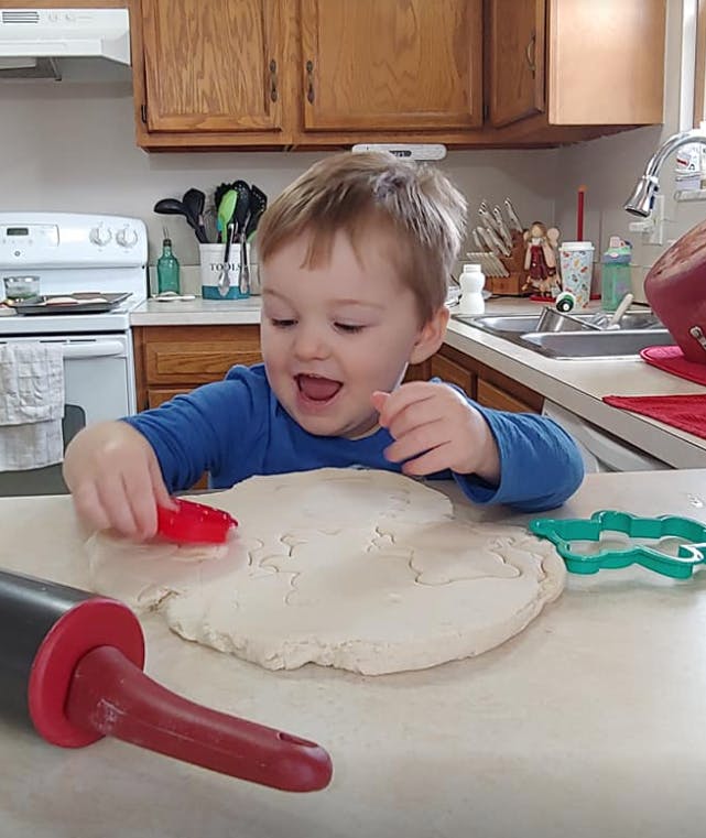 Child using a cookie cutter on dough in a kitchen