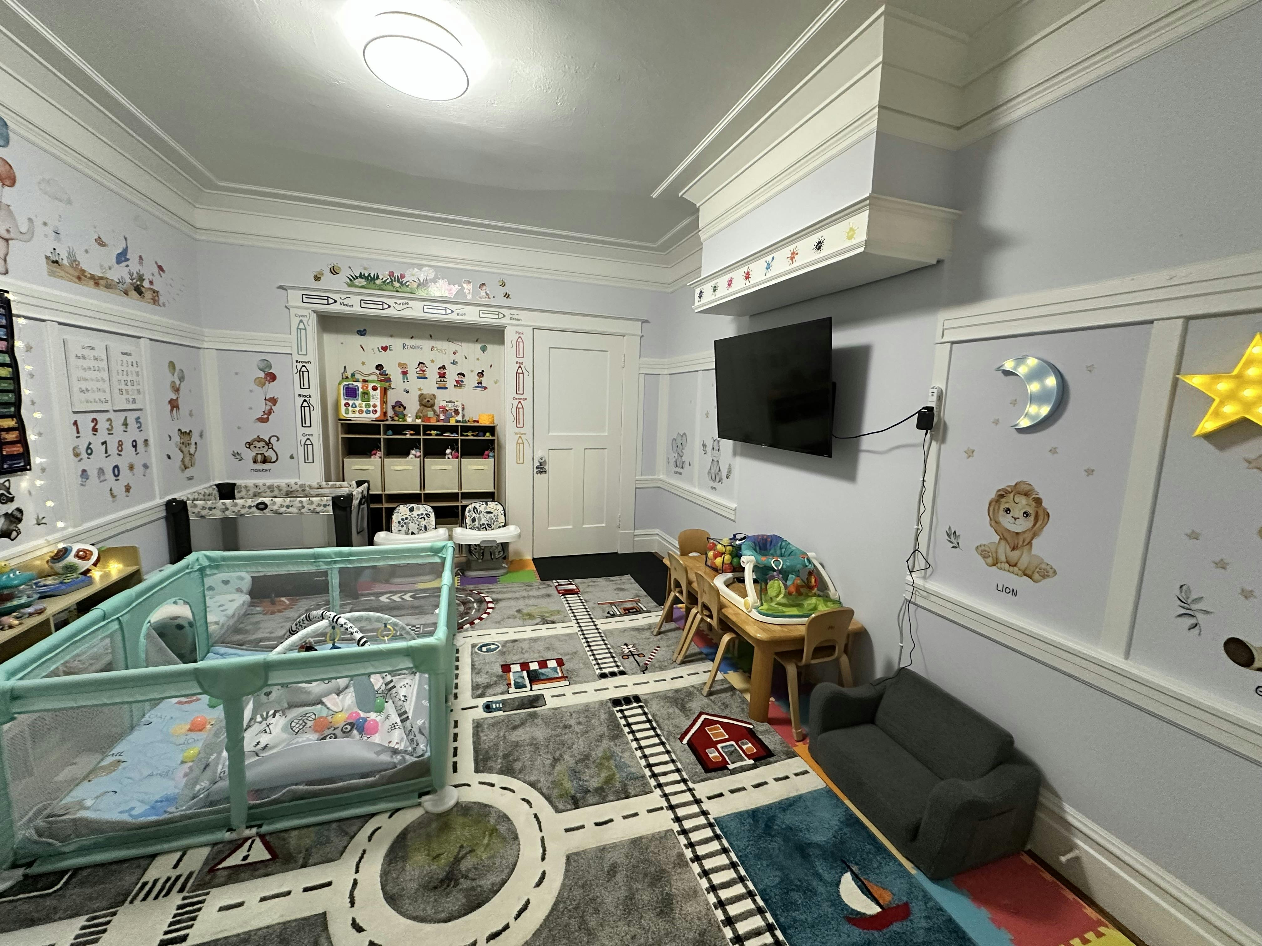 Playroom with a playpen, small table and chairs, and a road-themed rug