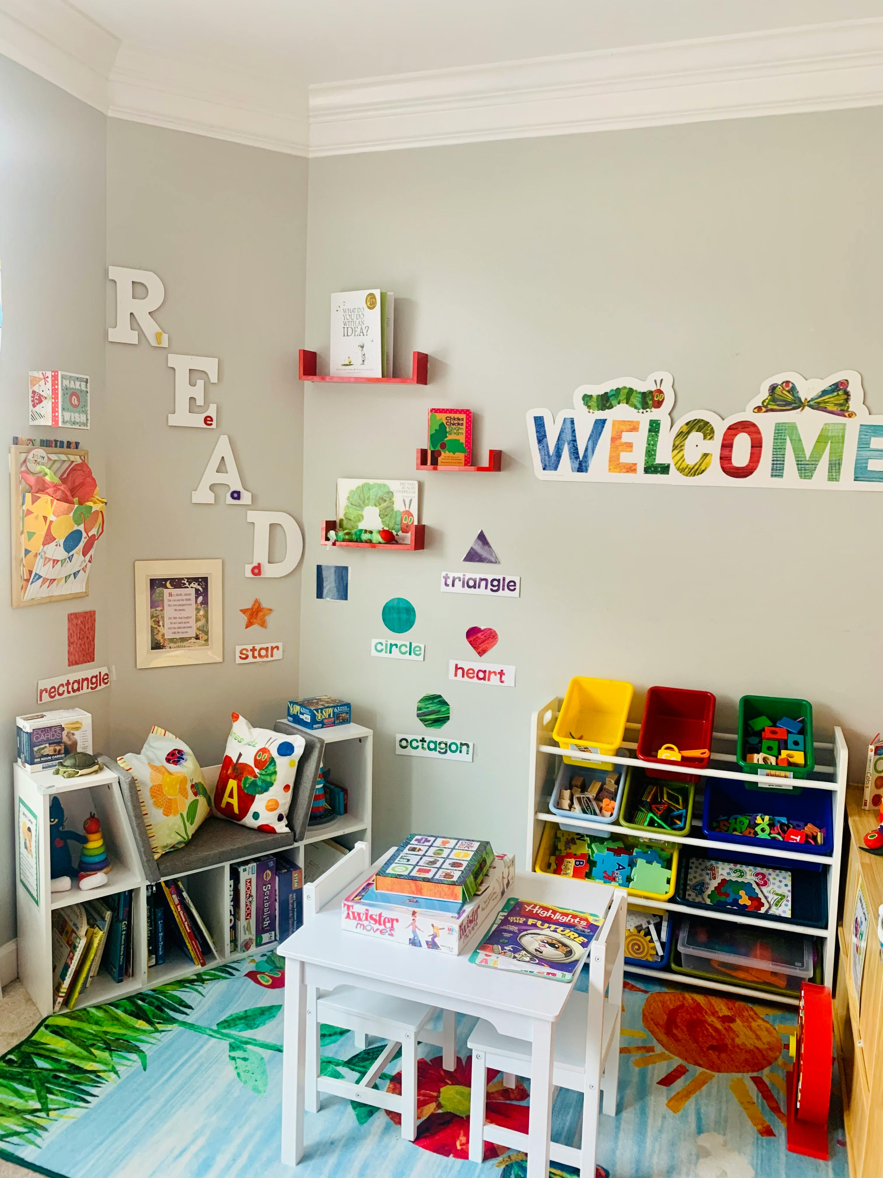 Children's playroom with a small table and chairs, bookshelves, and wall decorations