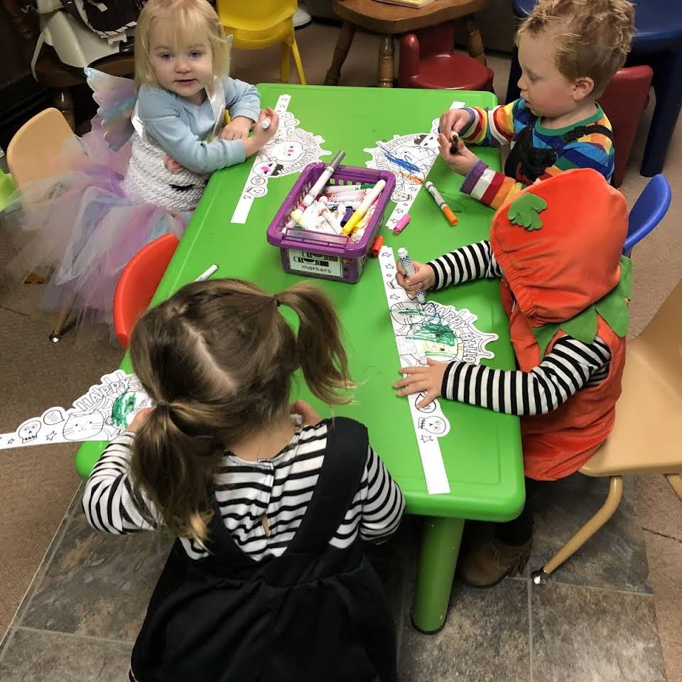 Three children coloring at a green table