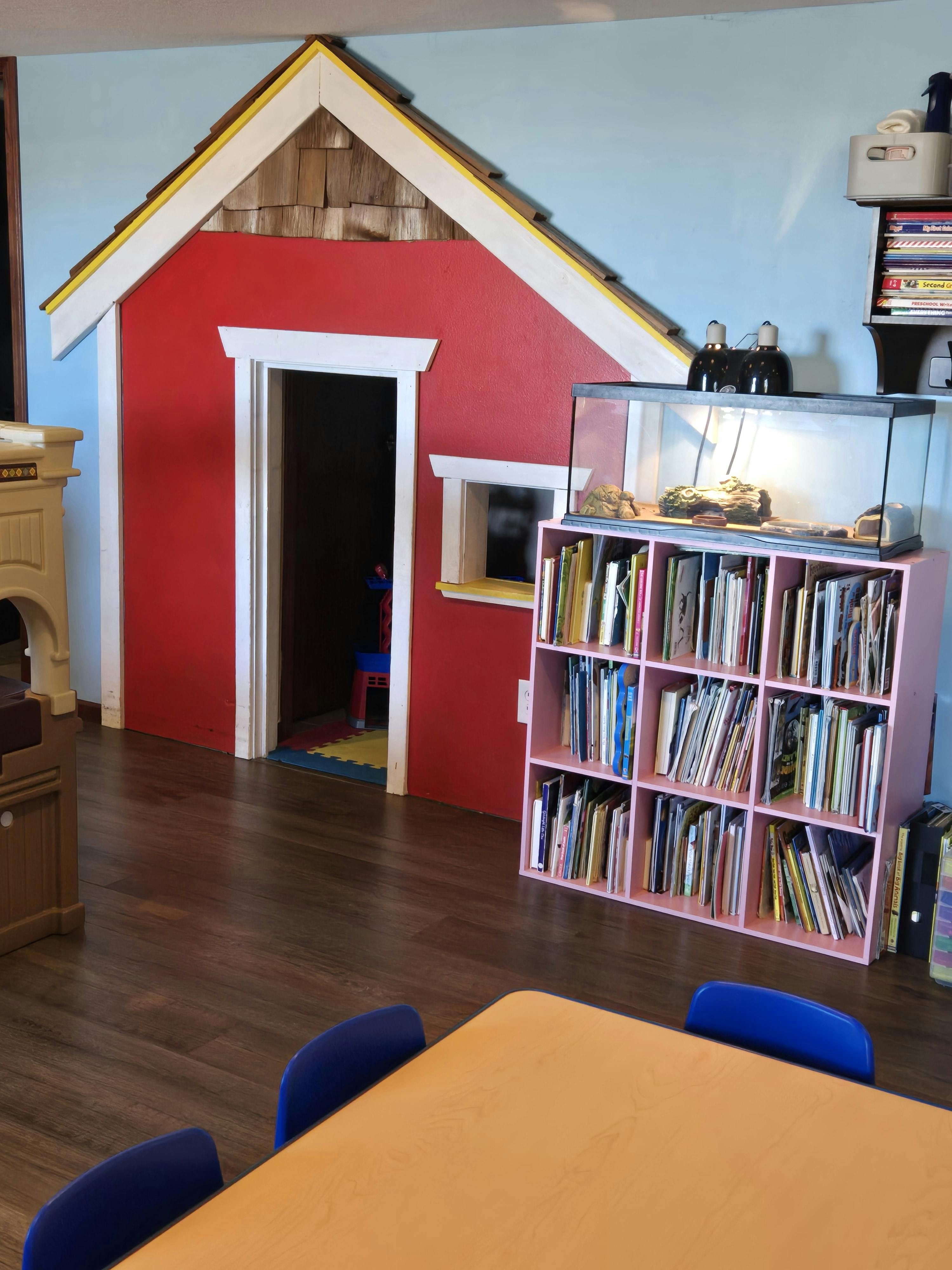 Red playhouse with a bookshelf and a terrarium on top