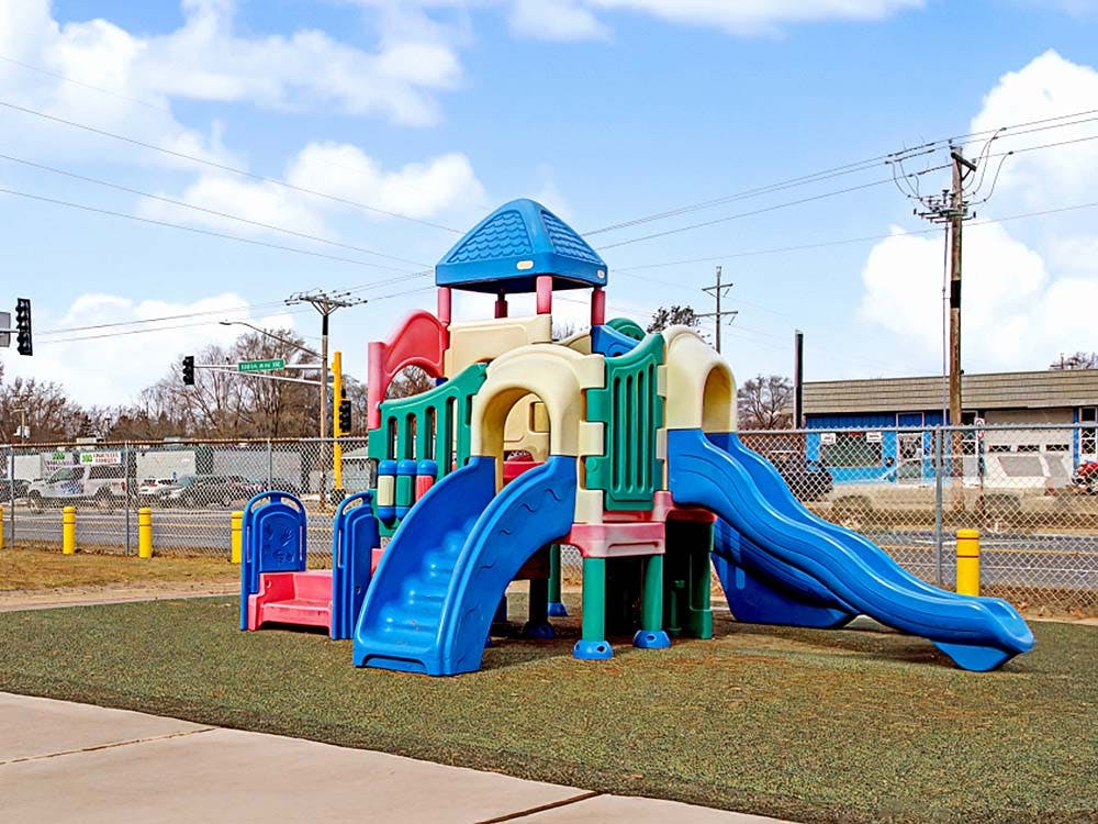 A colorful playground set with slides and climbing areas on artificial turf