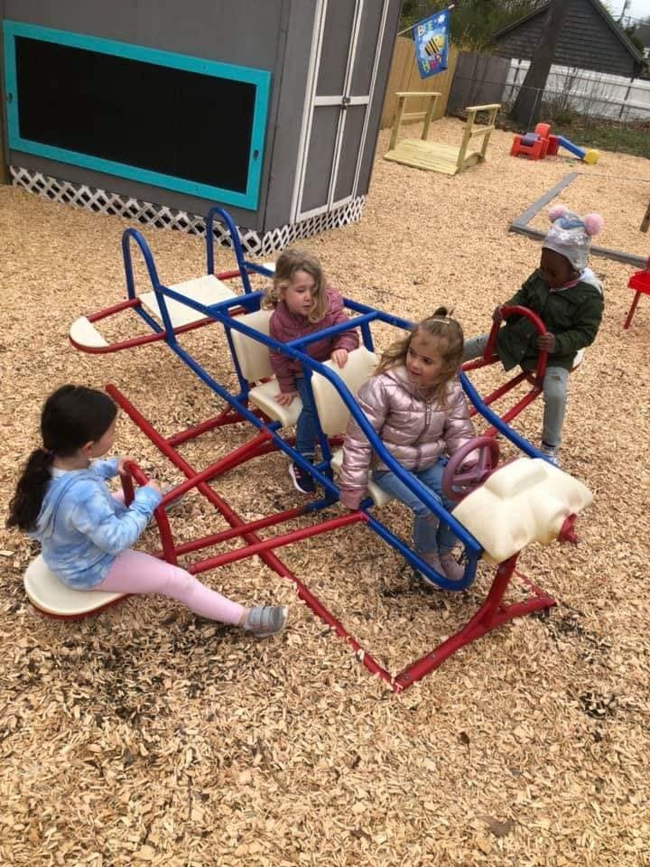 Four children playing on a seesaw in a playground