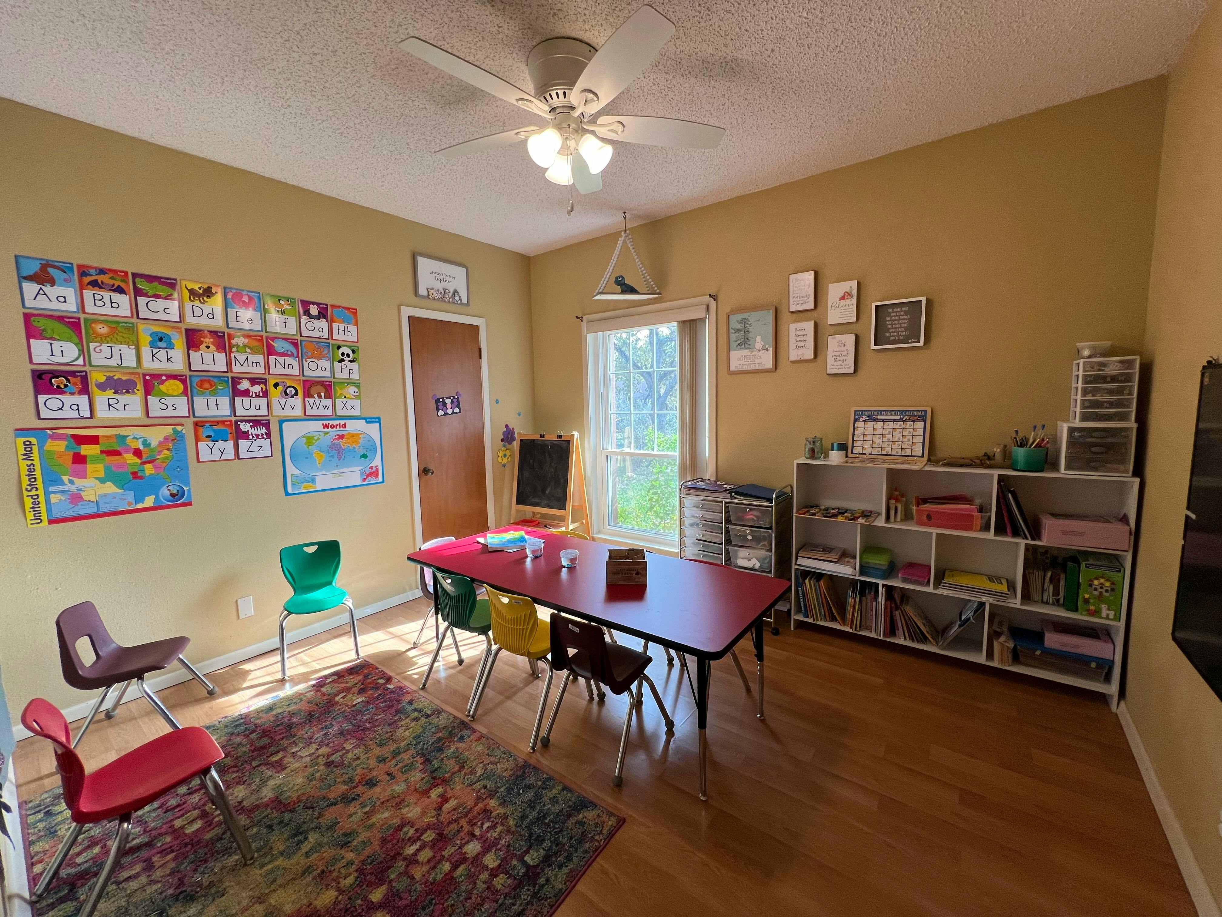 Classroom with a table and chairs, shelves, and educational posters on the wall