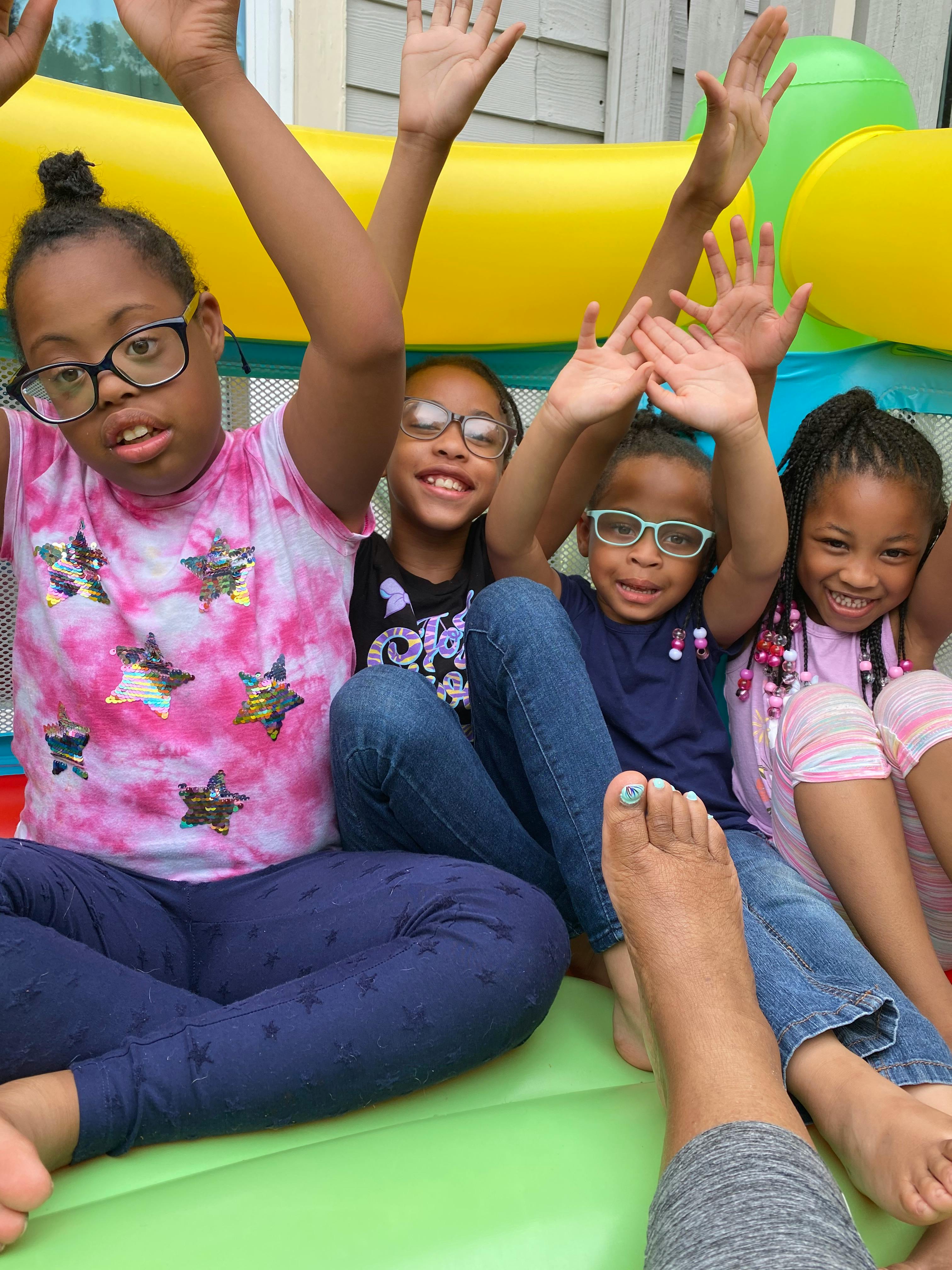 Four children with hands raised in an inflatable bounce house
