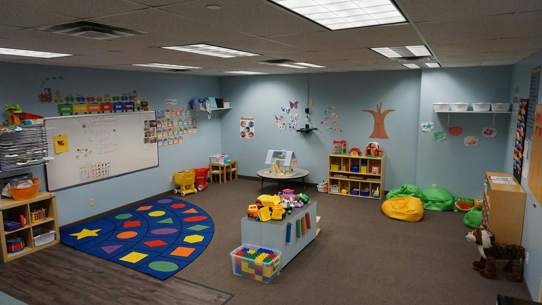 Playroom with a whiteboard, colorful rug, and toys