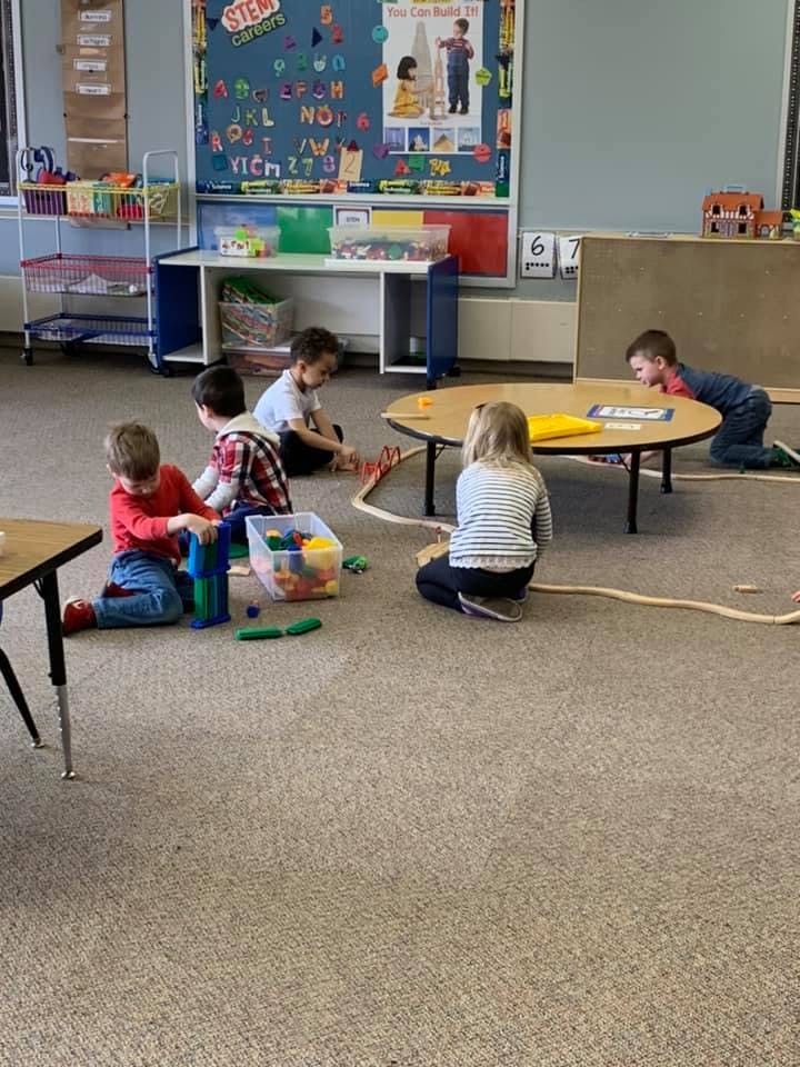 Children playing with toys on the floor in a classroom