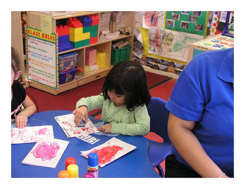 Child stamping on paper at a table in a classroom