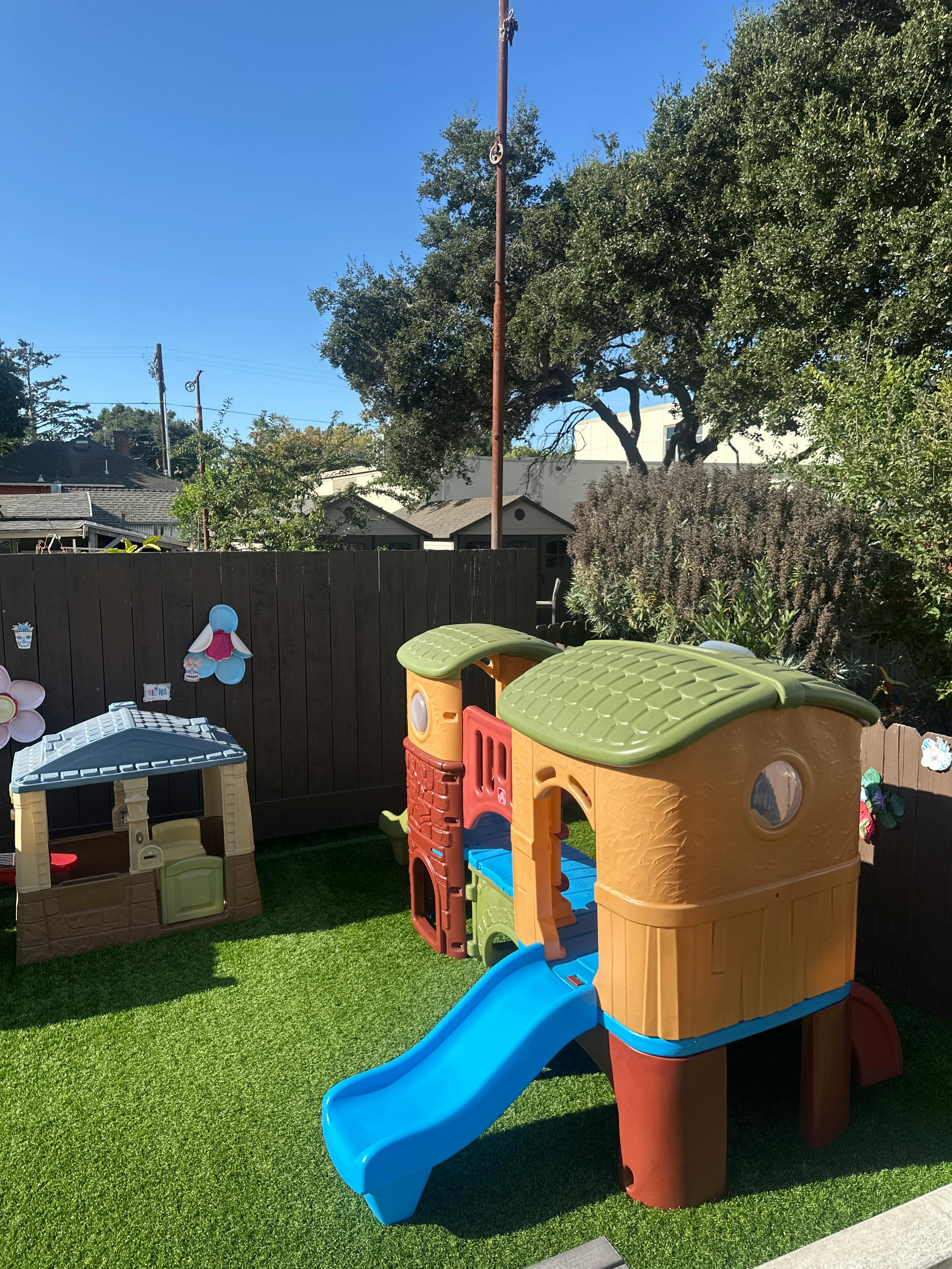 Playground with a slide and a small playhouse on artificial grass
