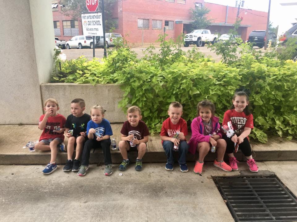 Six children sitting in a row outdoors