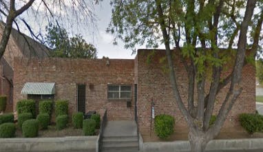 Brick building with a small awning and trimmed bushes