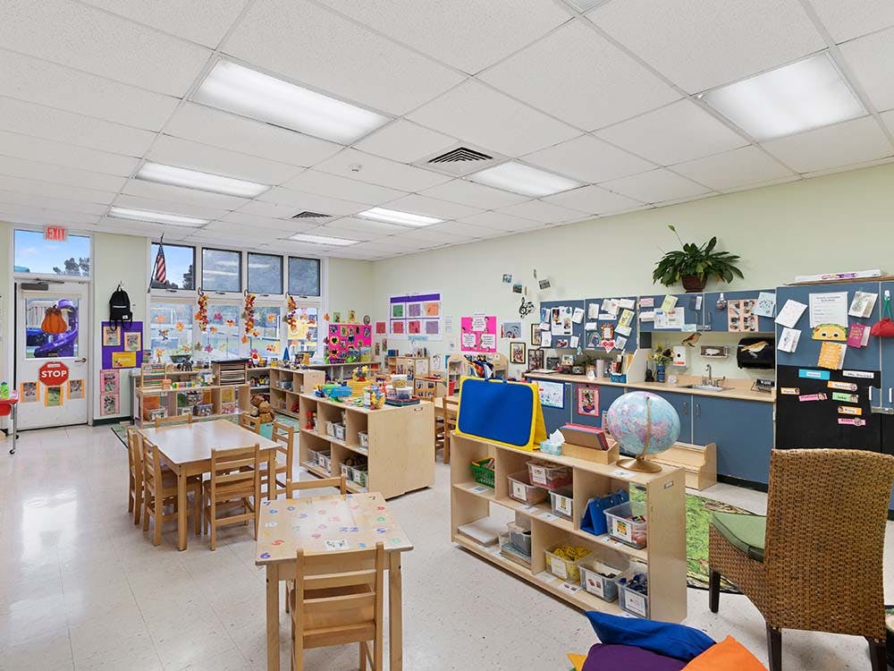 Empty colorful preschool classroom with small tables and chairs
