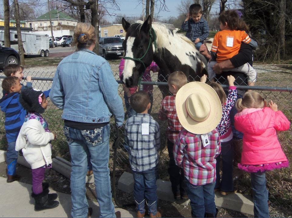 Adult and children gathered around a horse