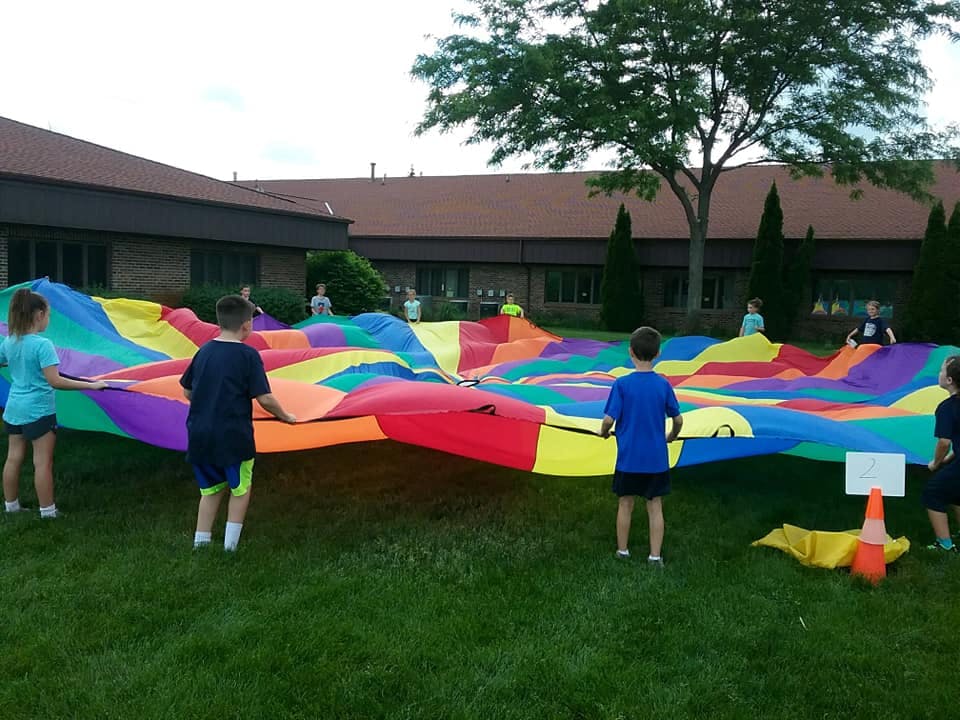 Children playing with a large colorful parachute on grass