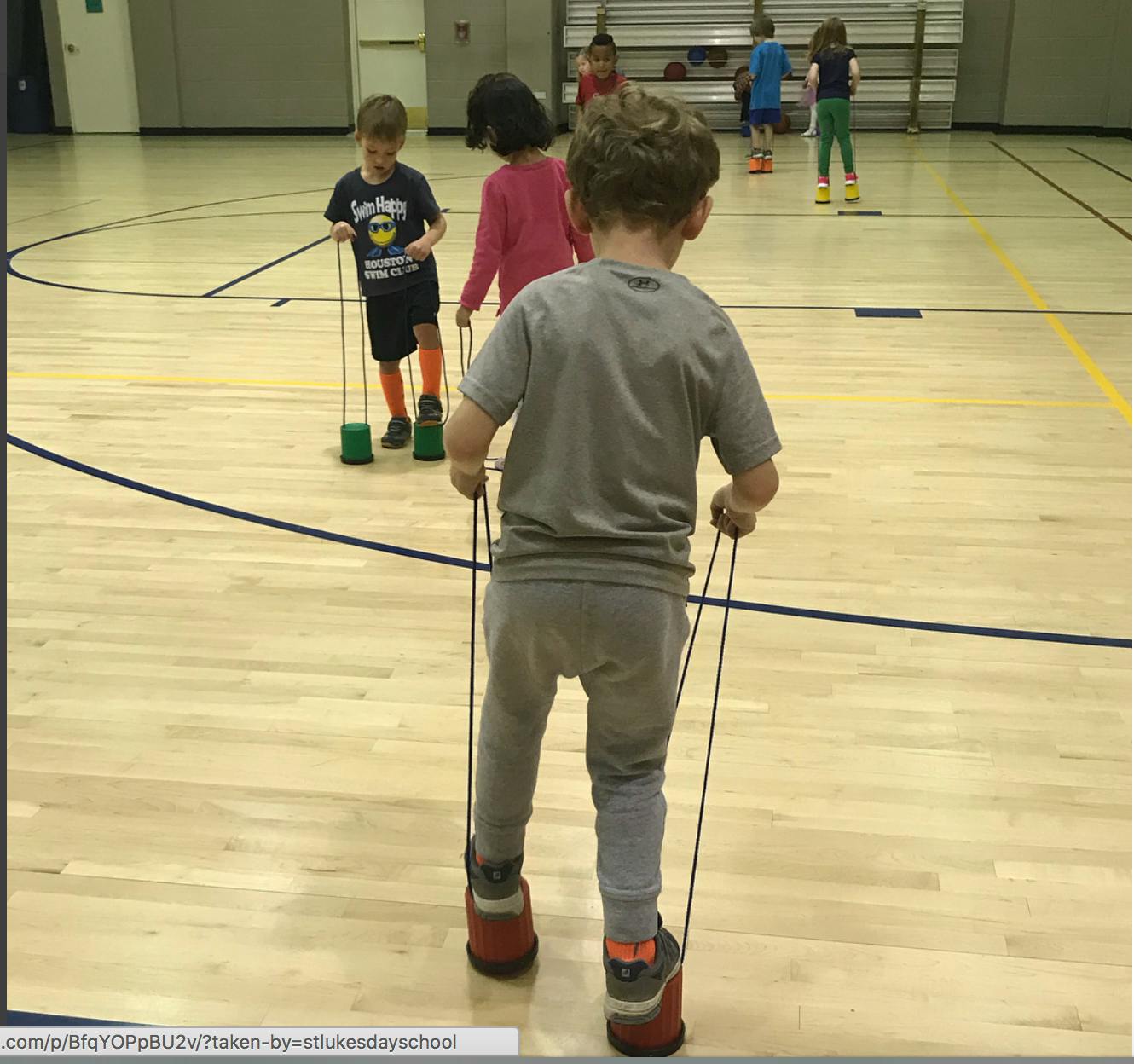 Children walking on can stilts in a gym