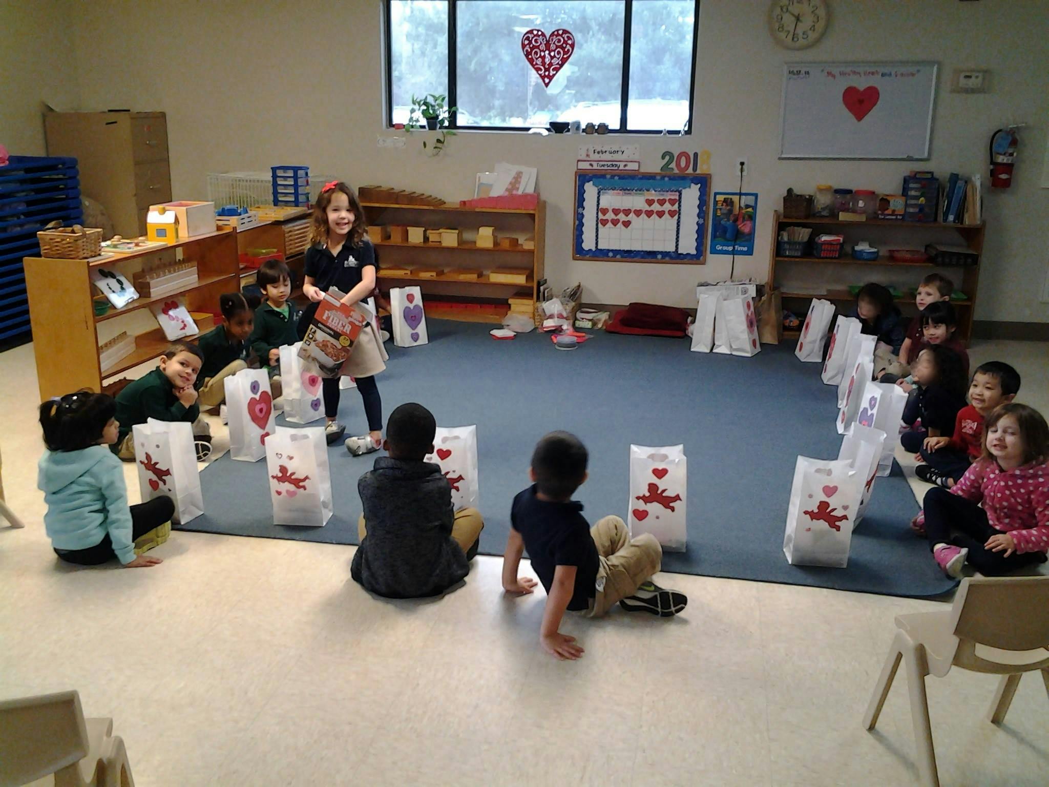 Children sitting in a circle with white bags decorated with hearts