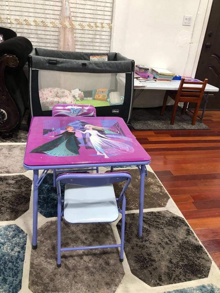 Child's purple table and chair with a playpen and white table in the background