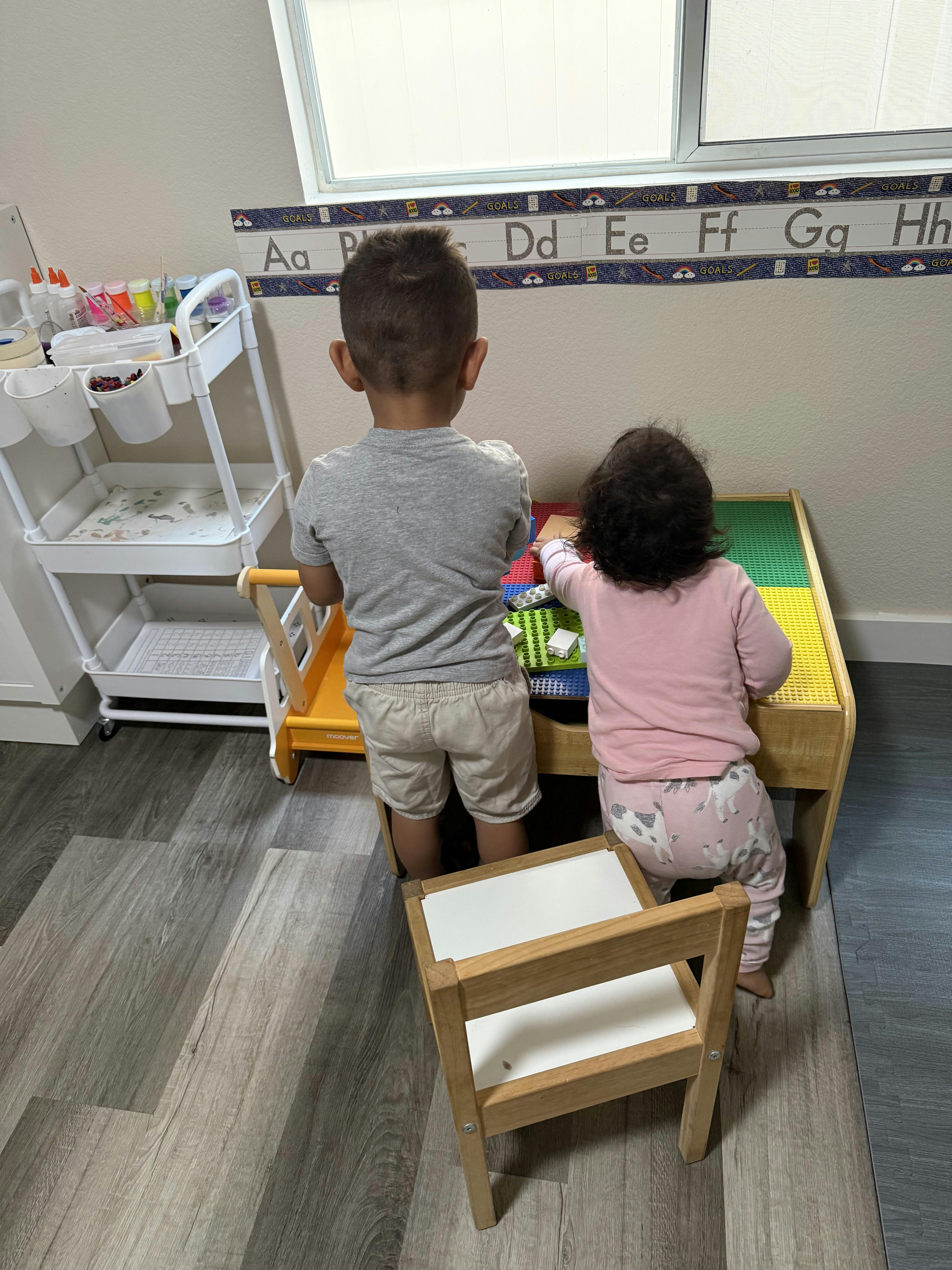 Two children playing at a table in a classroom