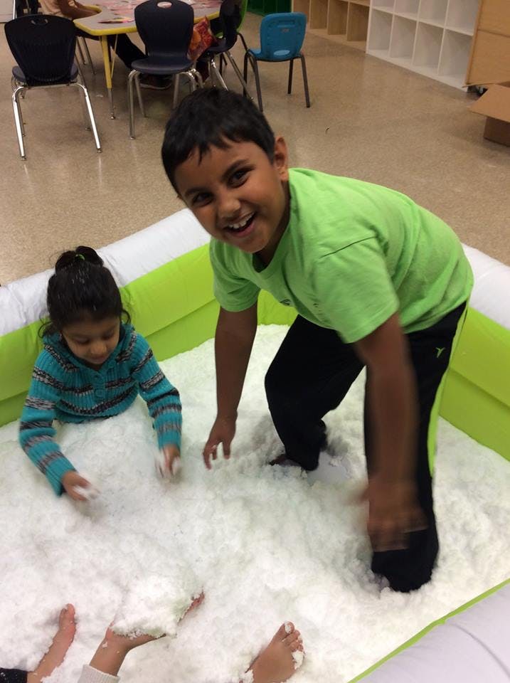 Two children playing in a white foam pit