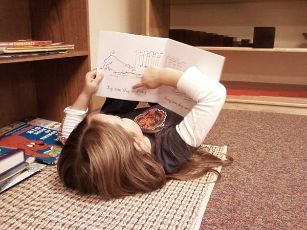 Child lying on floor reading a book