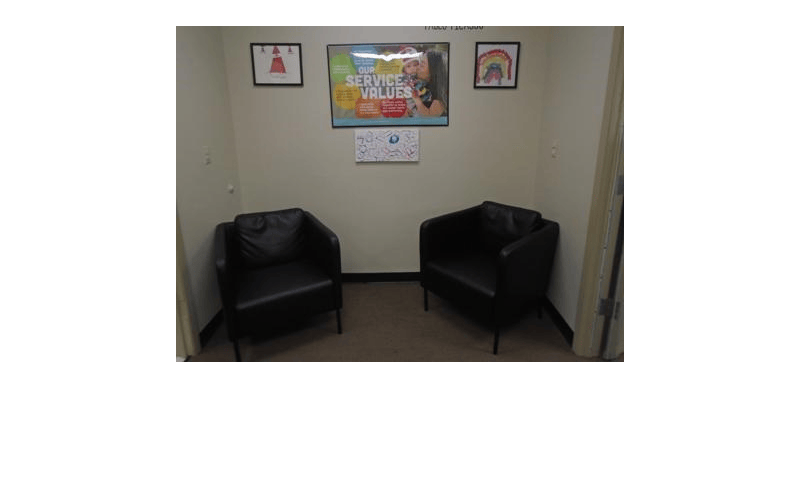 Two black chairs and a framed poster on a wall with text 'Our Service Values'