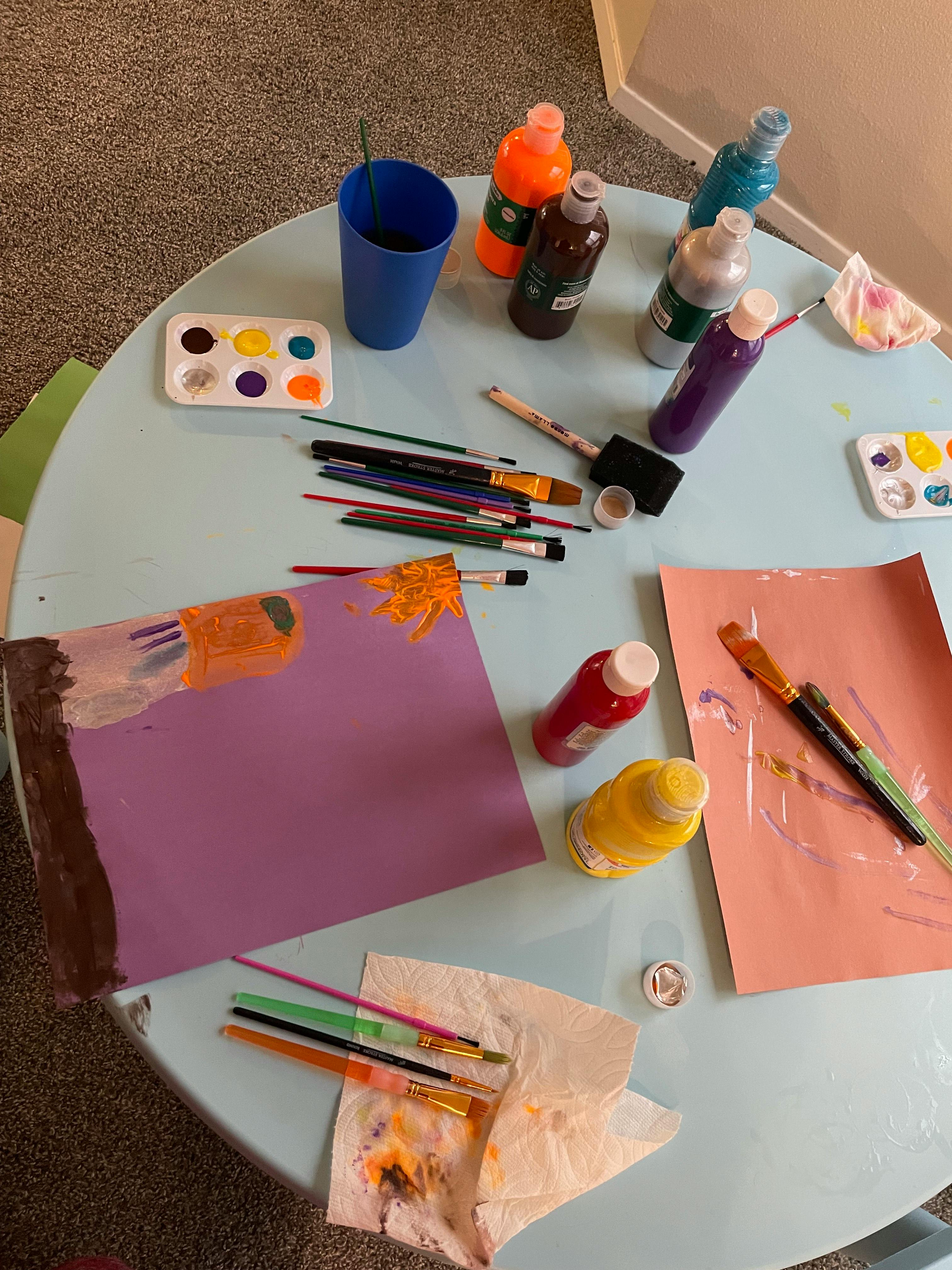 Art supplies and painted papers on a table
