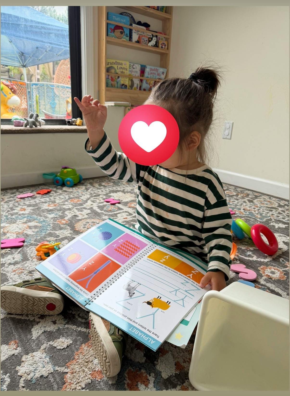 Child sitting on a rug and using an educational alphabet workbook