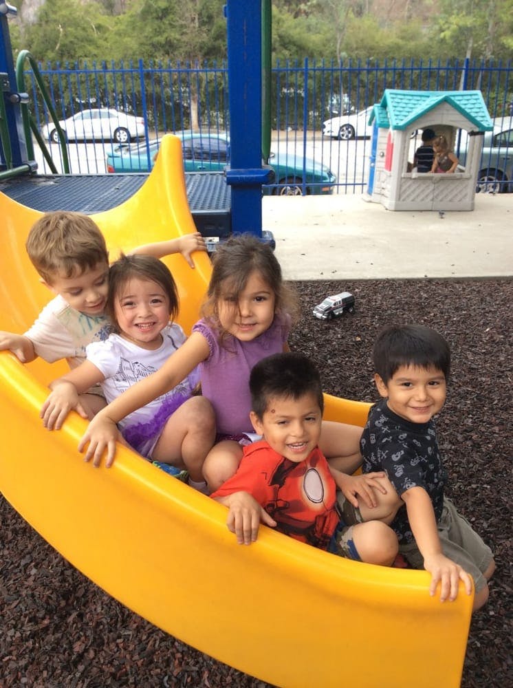 Five children sitting on a yellow playground slide