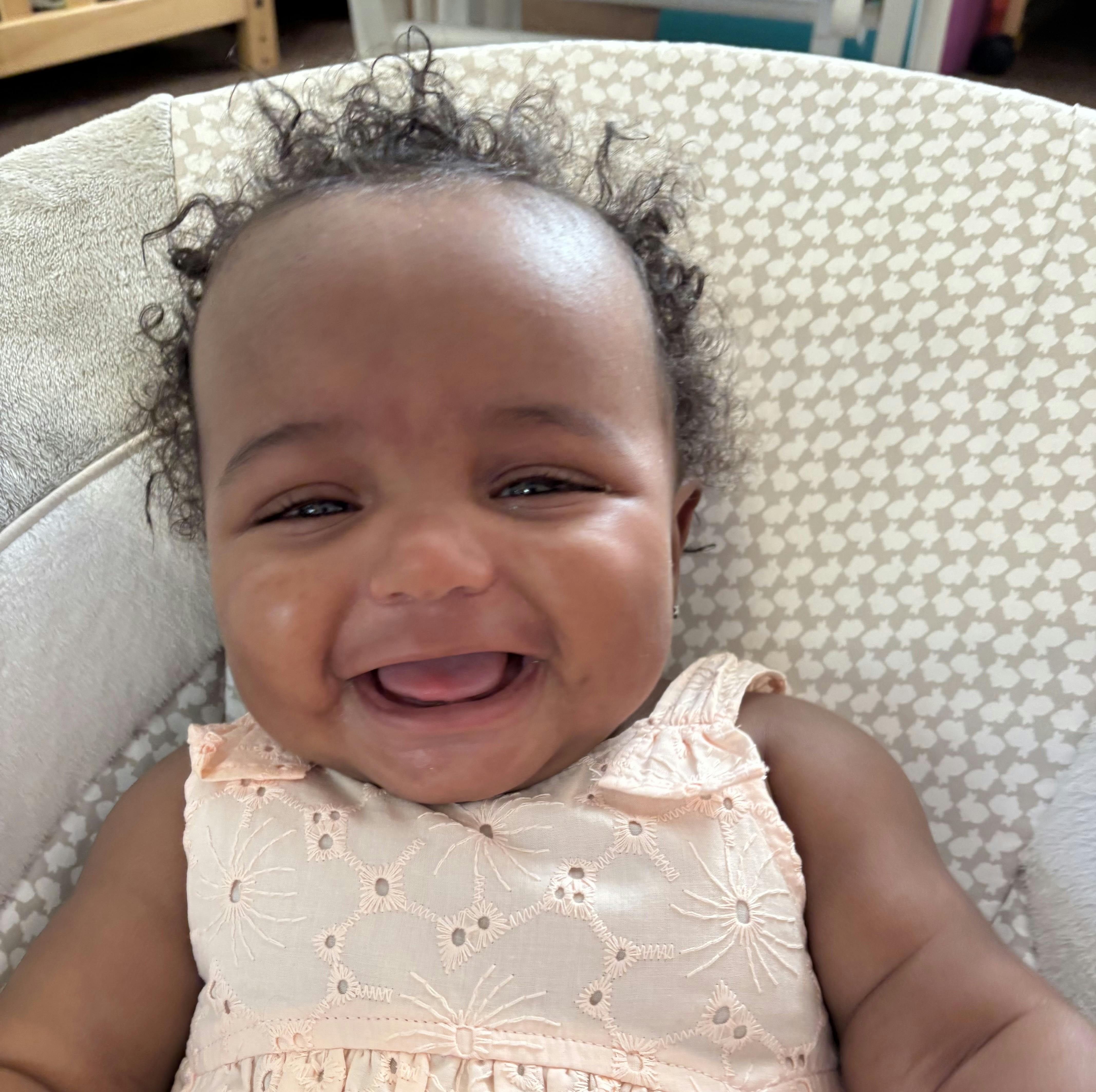 A smiling baby resting in a patterned seat