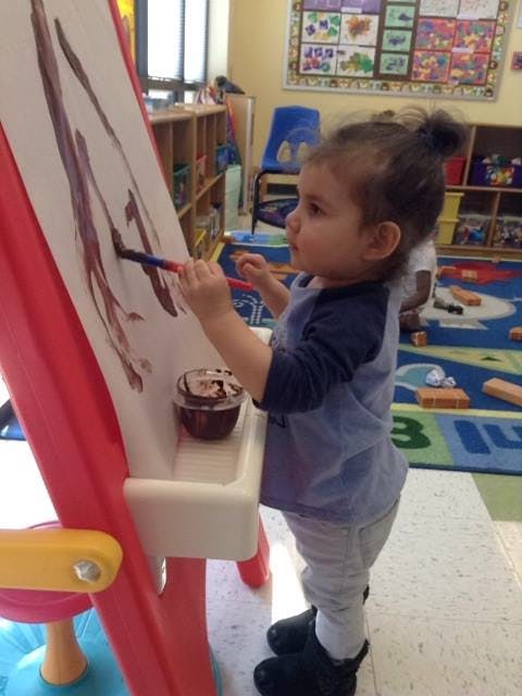 Child painting on an easel in a classroom