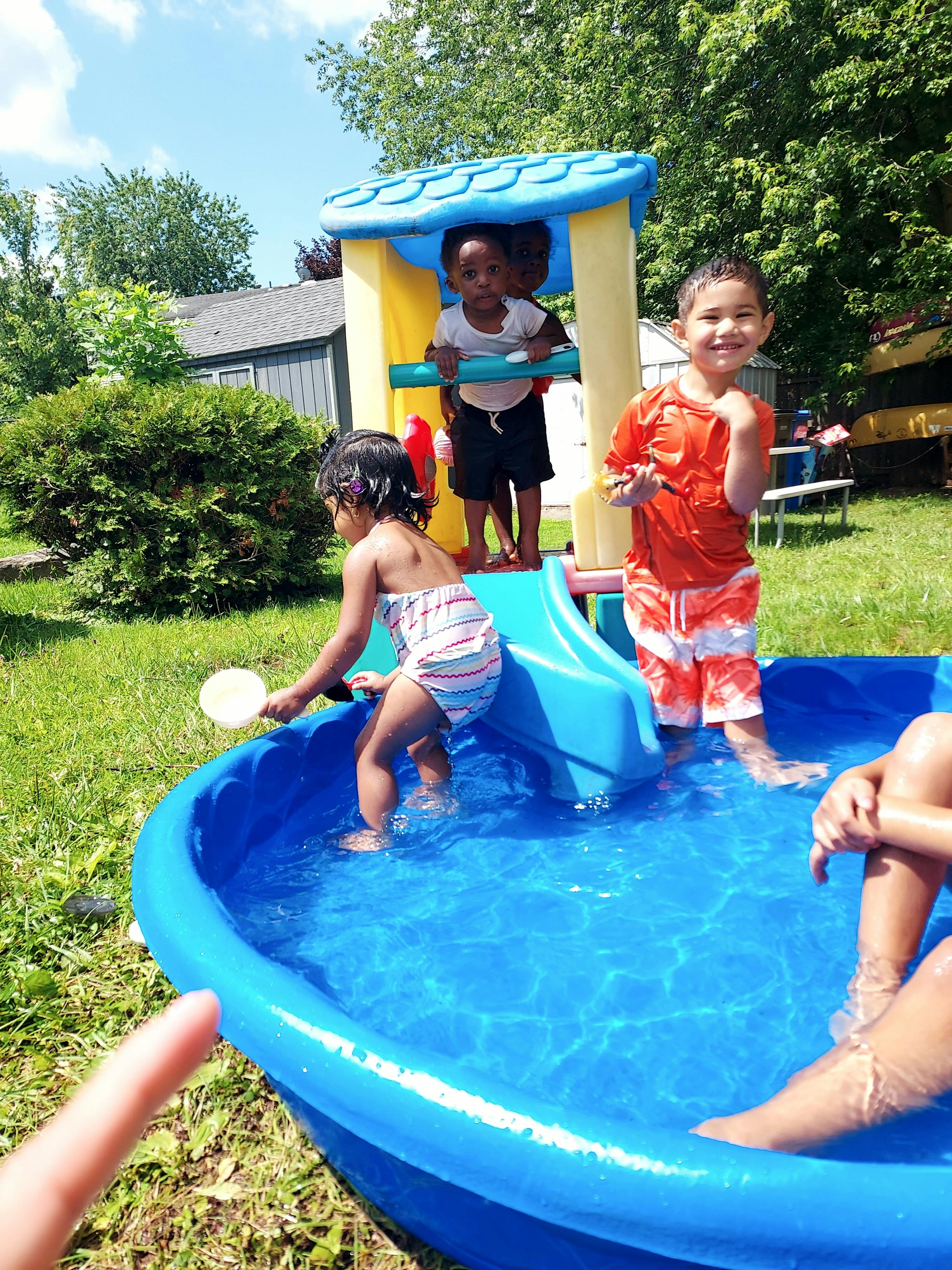 Children playing in a small blue pool with a play structure