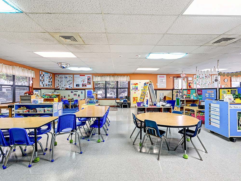 Classroom with small tables and chairs, and learning materials on walls