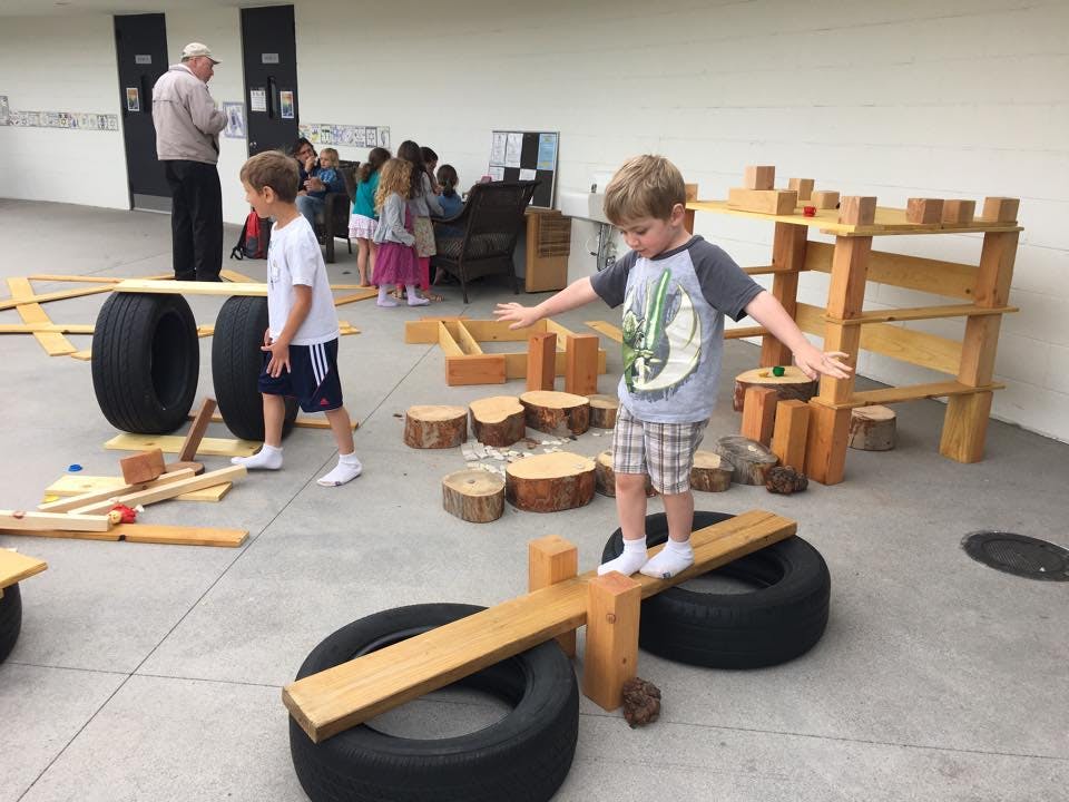 Child balancing on a wooden plank on tires