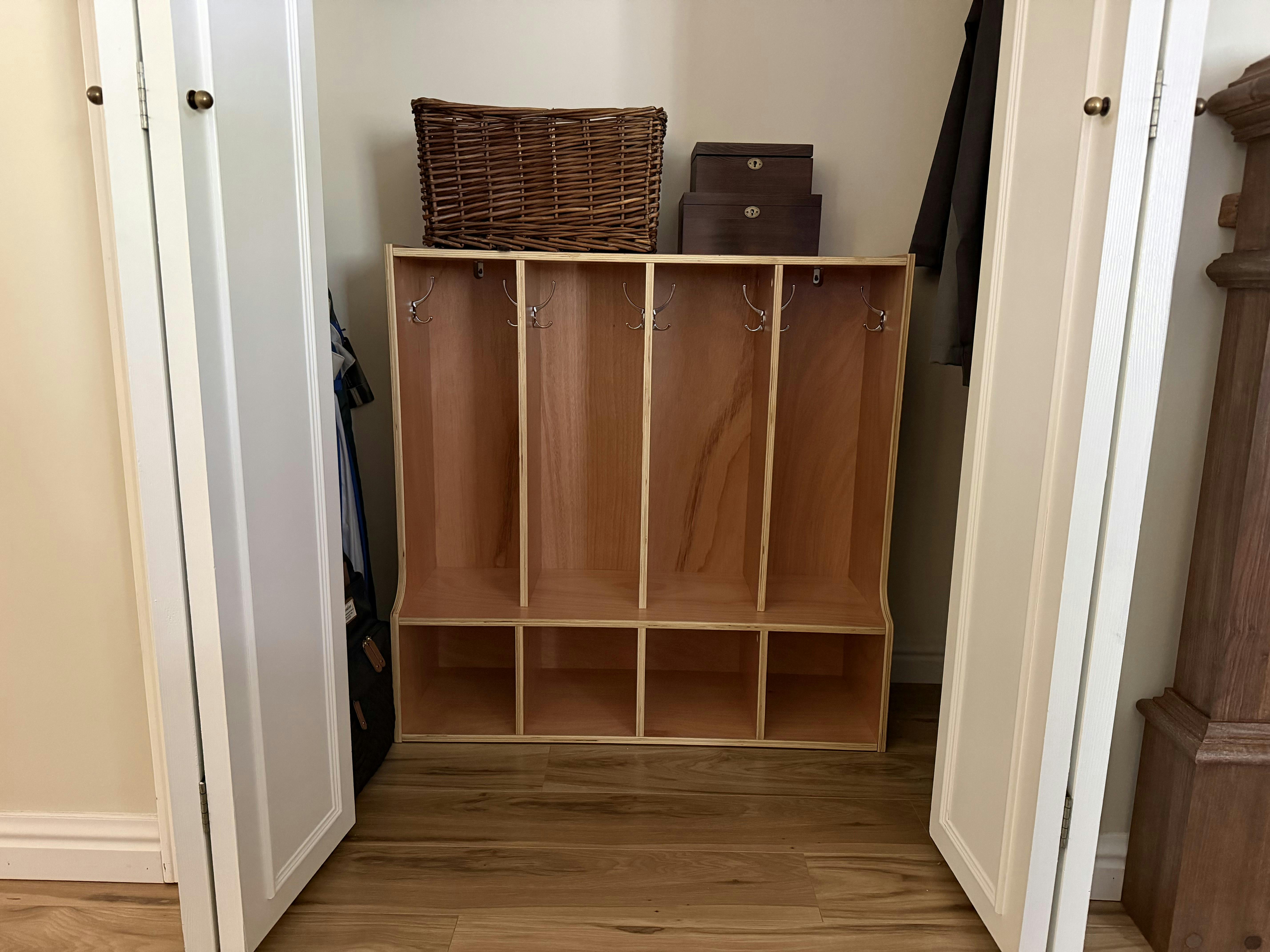 Wooden cubby storage unit with hooks inside an open closet