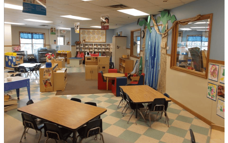Classroom with small tables and chairs, play kitchen, and window