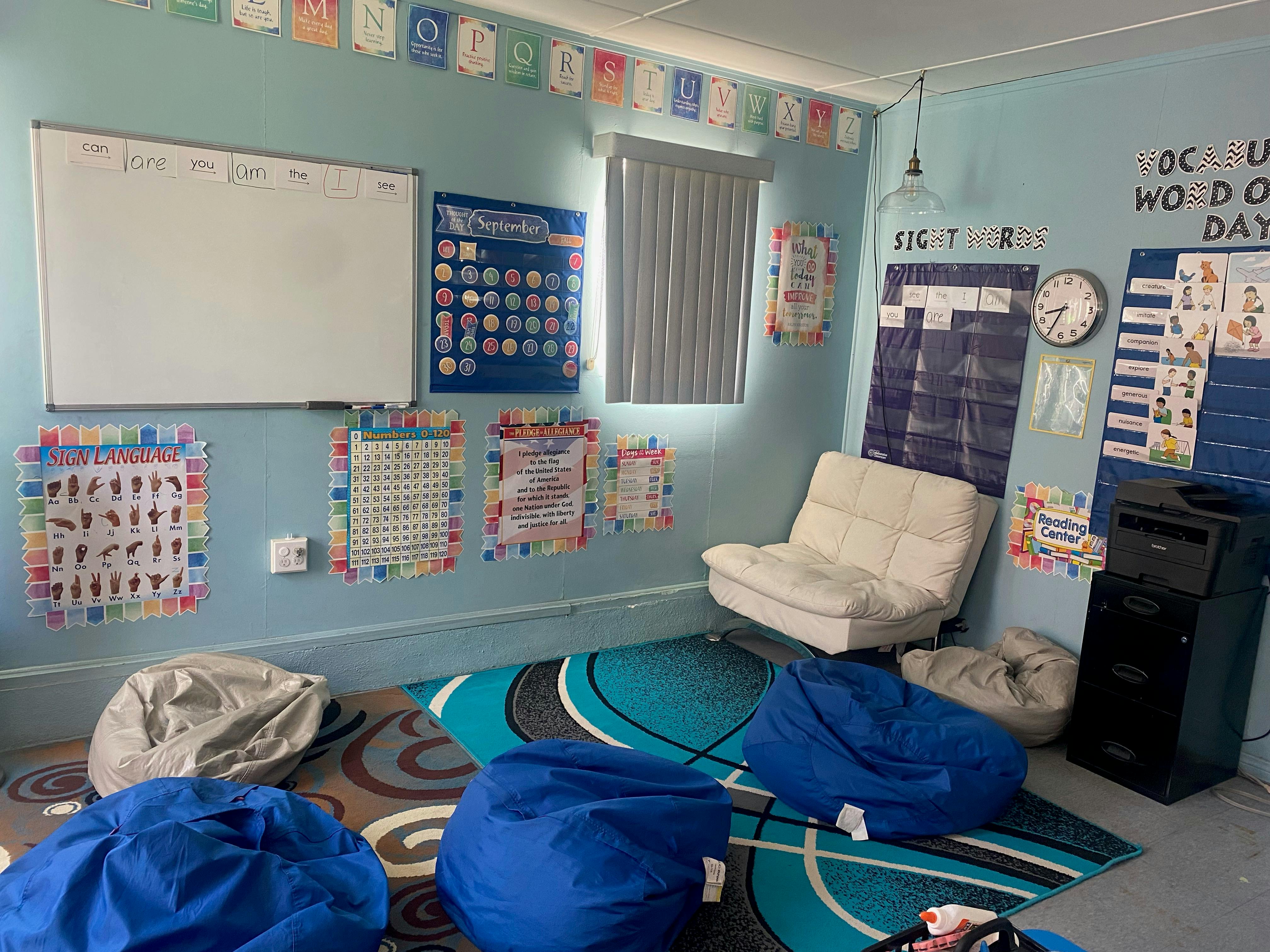 Classroom with whiteboard, calendar, posters, bean bags, and chair