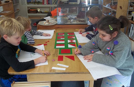Children drawing at a table with geometric shapes