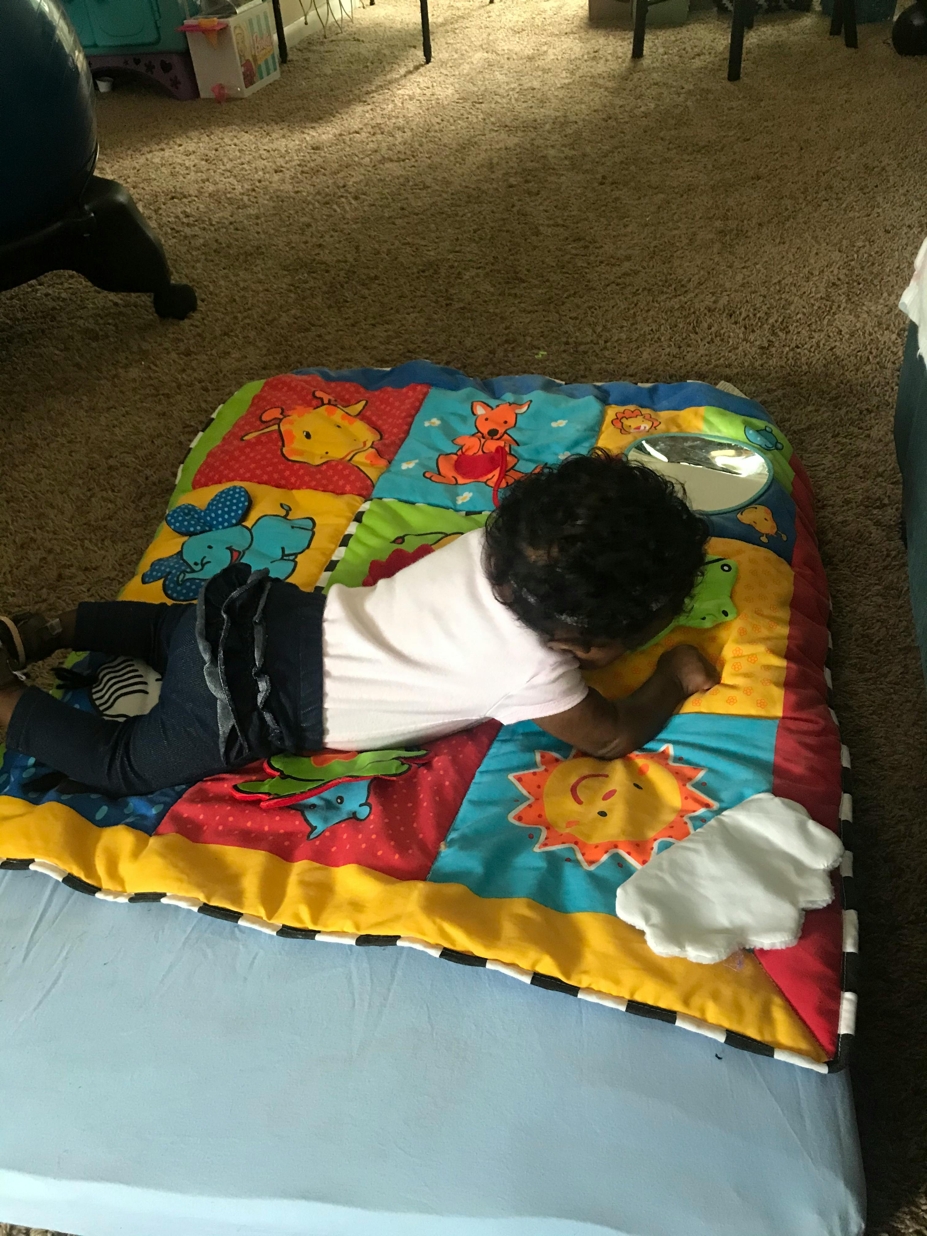 Child lying on a colorful play mat