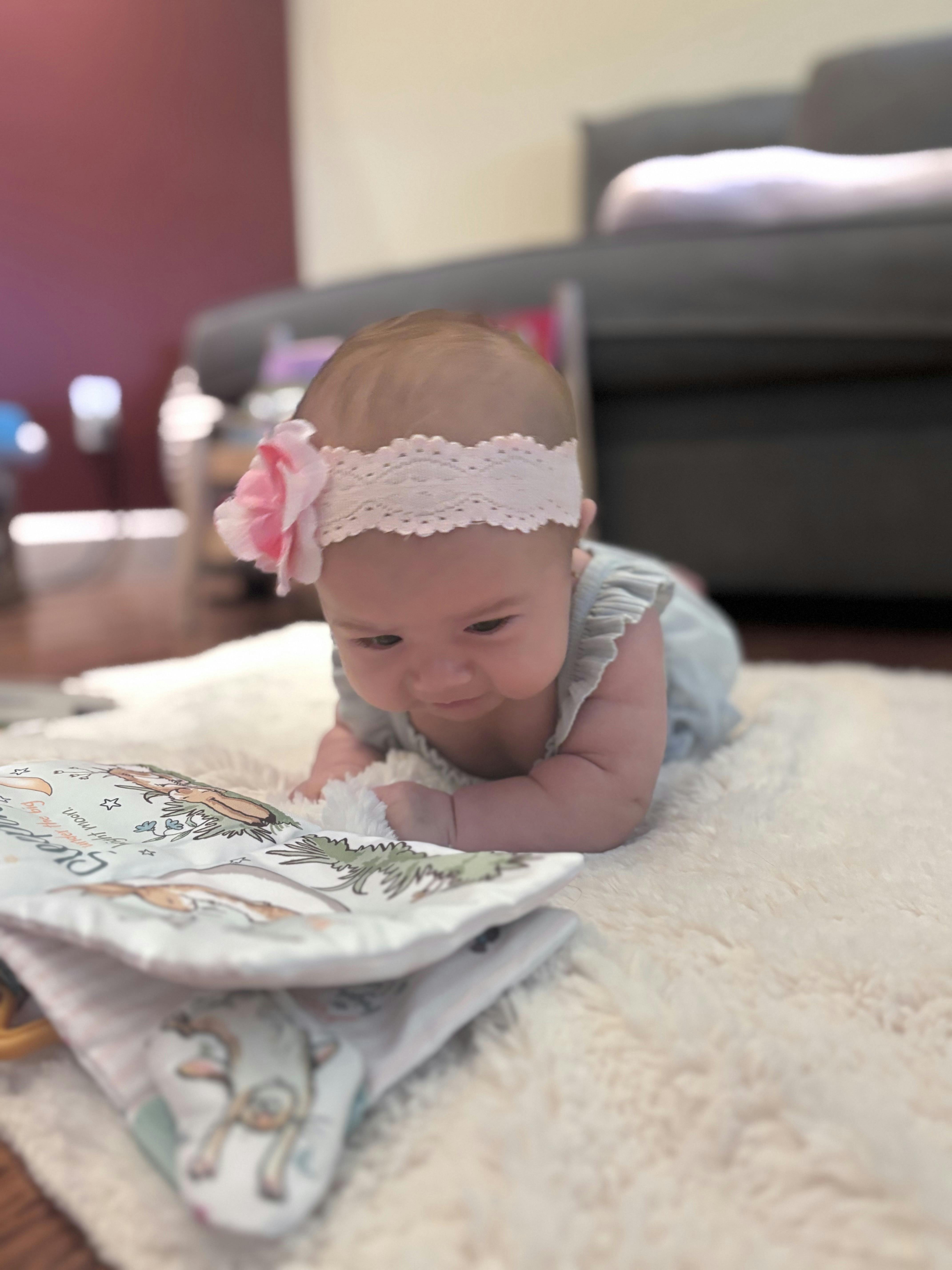 Baby lying on a rug looking at a soft book