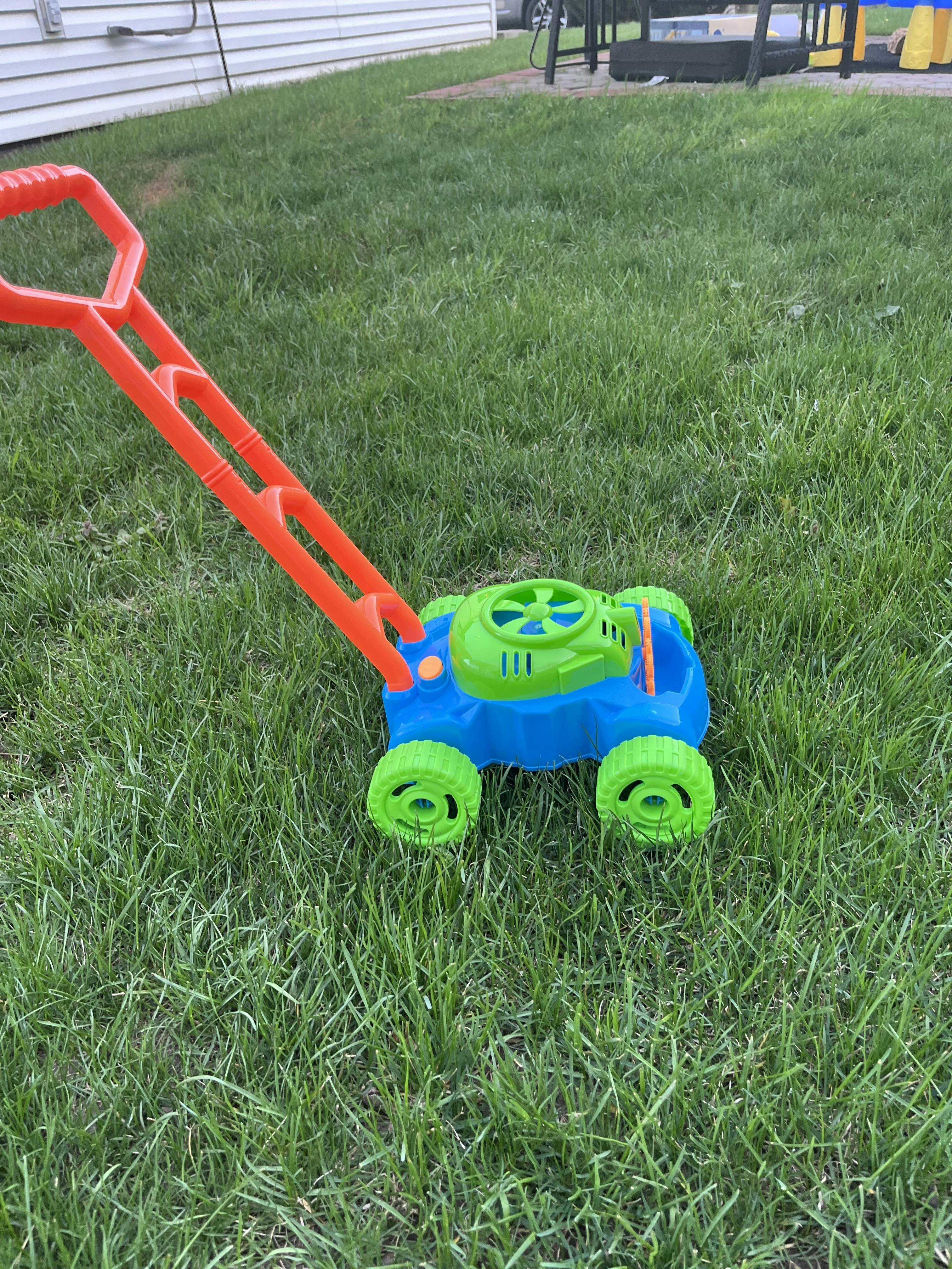 Plastic toy lawn mower on a grass lawn