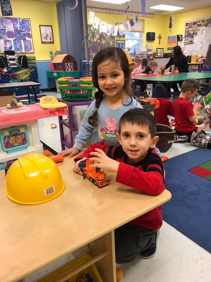 Two children playing with toys at a table in a classroom