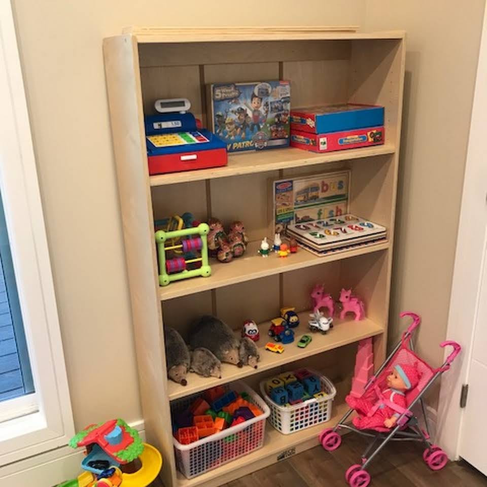 Wooden shelf with various toys including a cash register, board games, and a doll stroller