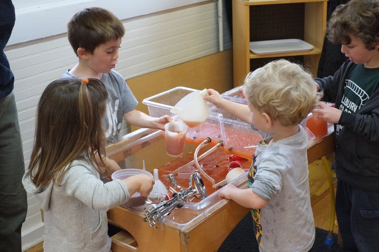 Children playing with water and containers at a sensory table