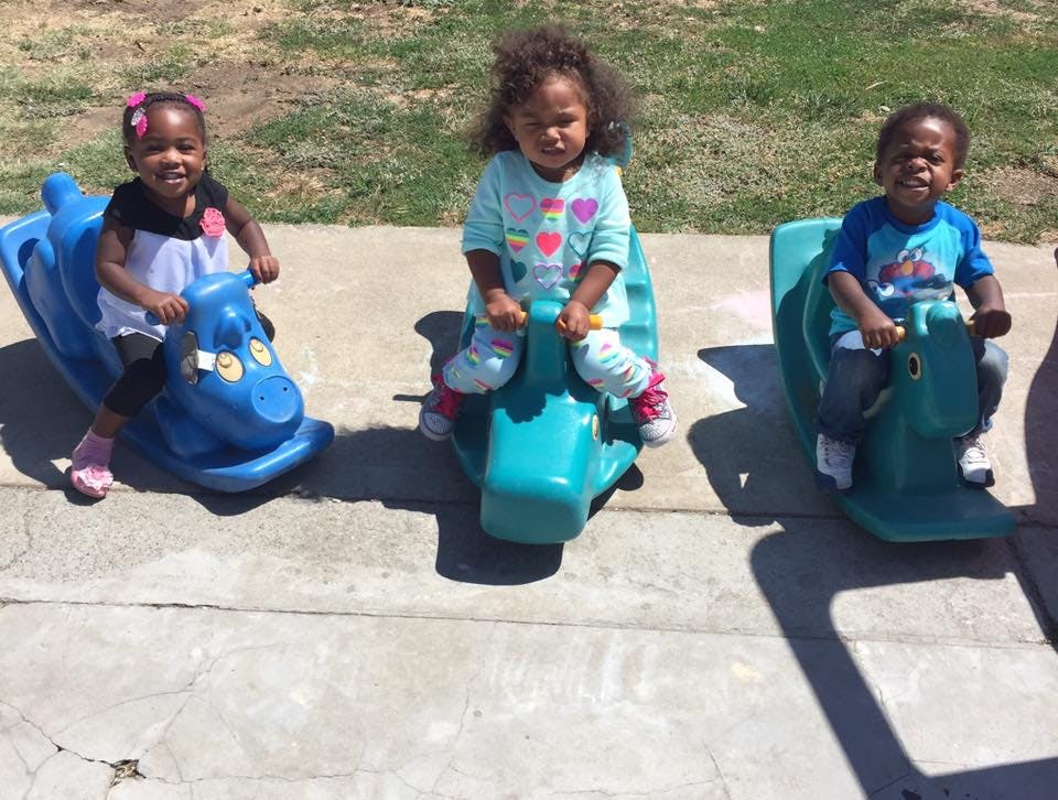 Three children on plastic rocking toys outdoors